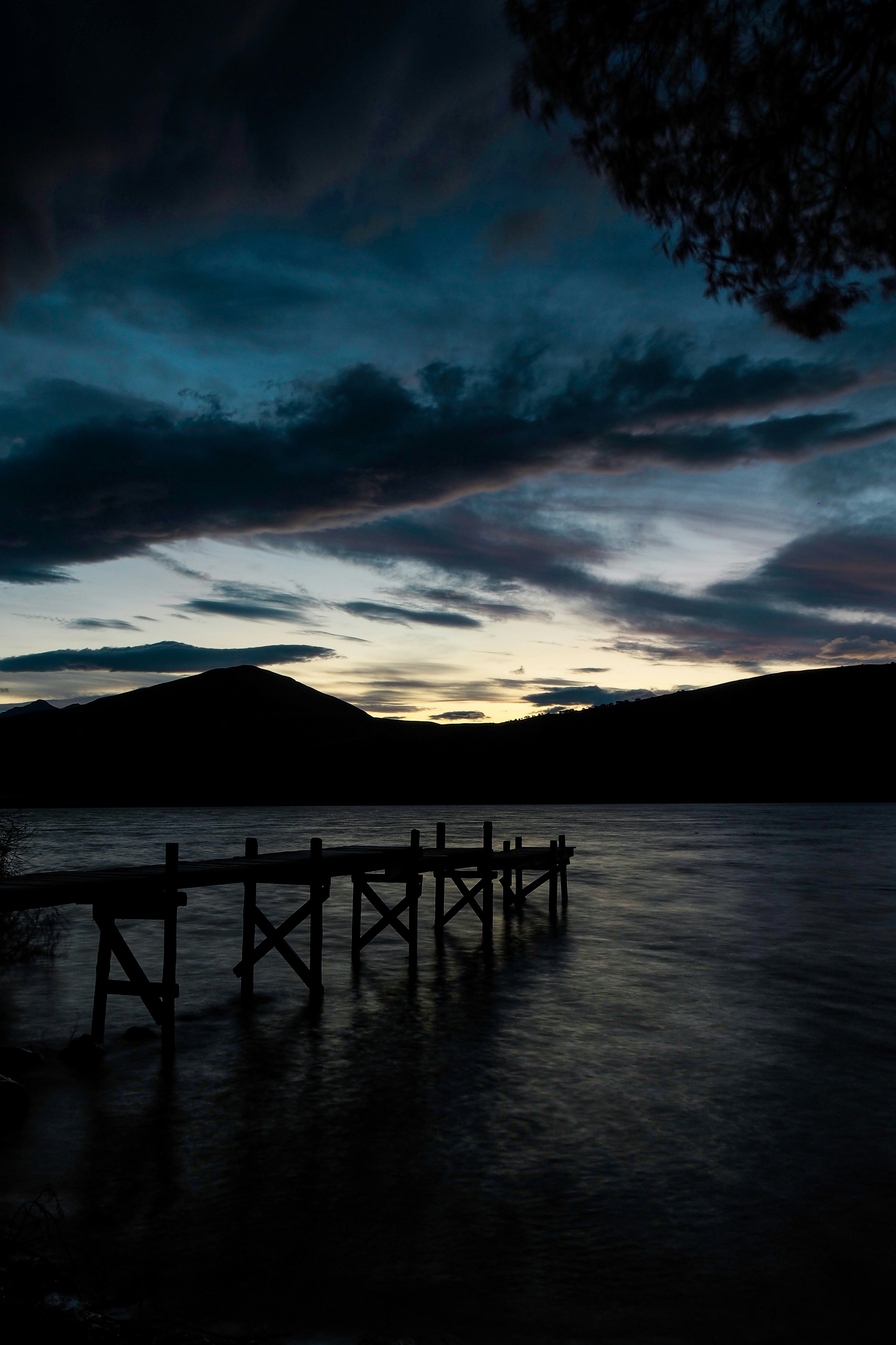 silhouette of mountain near body of water during sunset